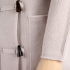 Close-up of a textured grey duffle coat with buttons and a sleeve.