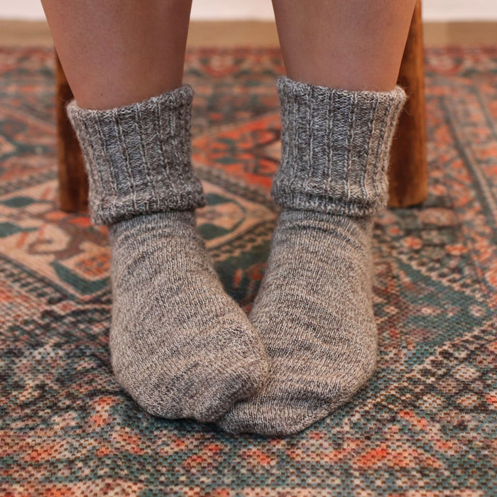 Gray socks worn on a patterned rug