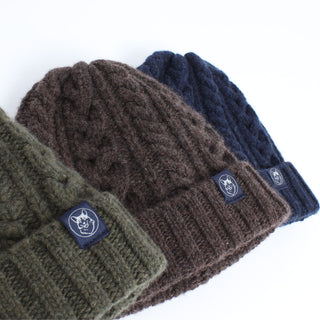 Three knit hats in green, brown, and navy on a white background