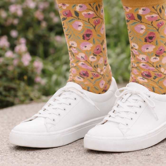 White sneakers with floral-patterned socks against a blurred natural background