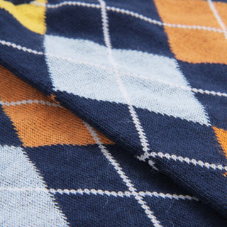 Close-up of a fabric with a blue, orange, and white argyle pattern.