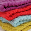 Stack of folded knitted blankets in purple, red, blue, and yellow.