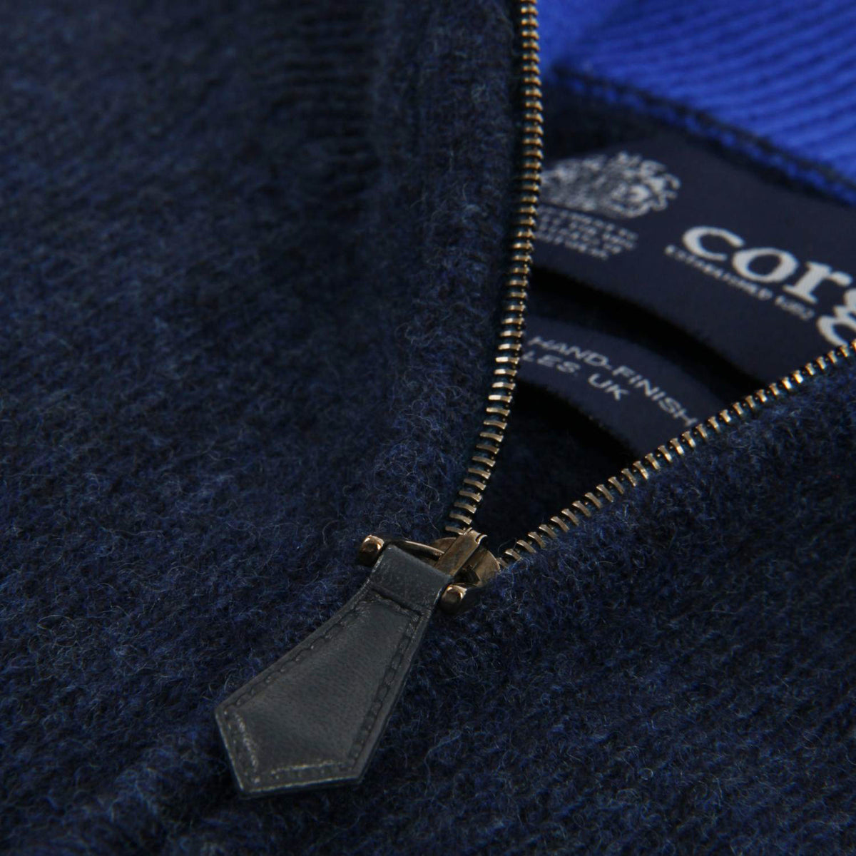 Close-up of a navy blue jacket with a gold zipper, featuring the brand 'core'.