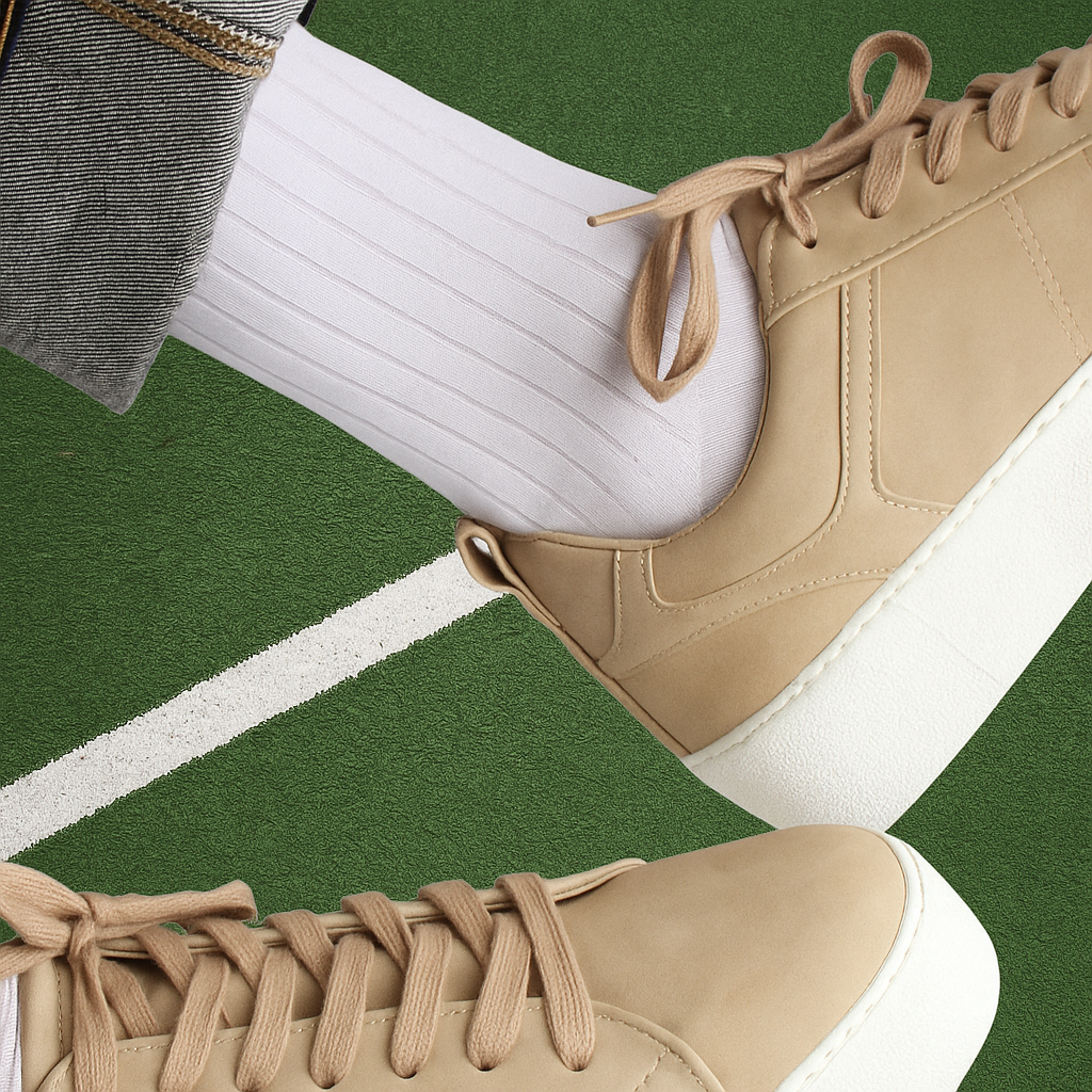 Beige sneakers with white socks on a green and white striped background