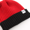 Red and black beanie with a brand label on a white background