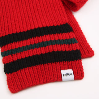 Red knitted scarf with black and green stripes and a visible brand label on a white background