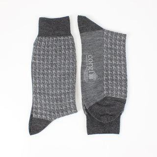 A pair of men's formal houndstooth merino wool socks in grey, showing the pattern and texture.