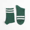 Two green socks with white stripes on a light gray background