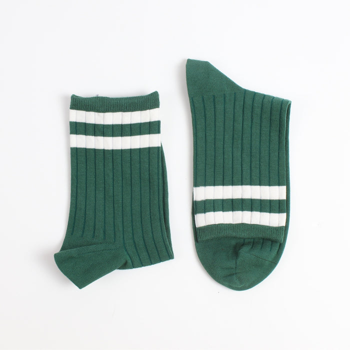Two green socks with white stripes on a light gray background