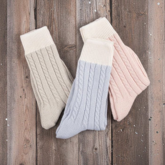 Three pairs of knitted socks in beige, light blue, and pink on a white background