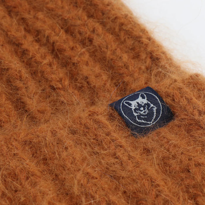 Close-up of a gold textured fabric with a logo tag featuring a Corgi dog  design.