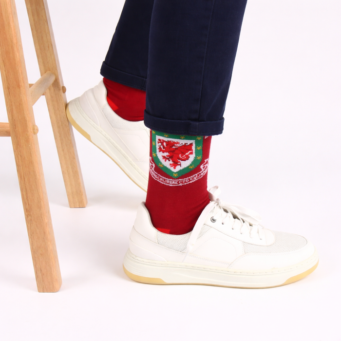 Red socks with a emblem worn by a person in white sneakers on a light background