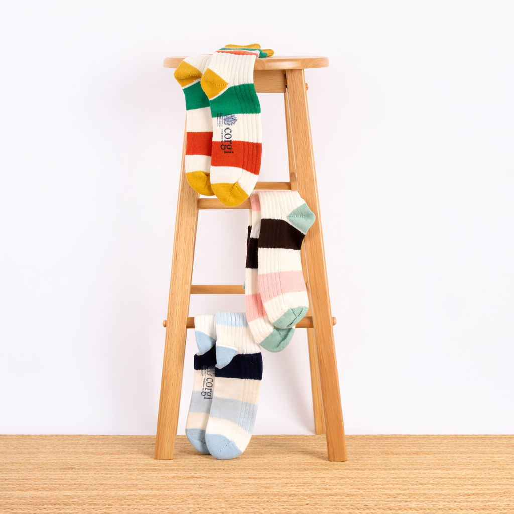 Colourful striped socks on a wooden stool against a white background