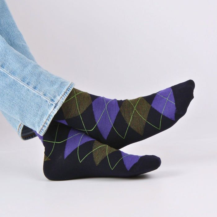 Person wearing black socks with purple and green pattern on a white background