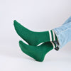 Green socks with white stripes worn with light blue jeans on a white background