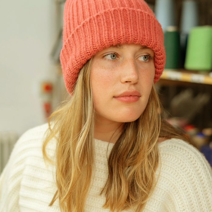 Person wearing a orange knit beanie and white sweater in an indoor setting