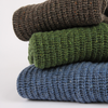 Stack of three folded knitted sweaters in brown, green, and blue on a white background