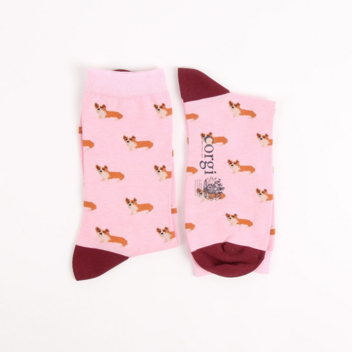 A pair of pink crew socks with a repeating corgi print and dark burgundy heels, toes, and cuffs, displayed on a clean white background.
