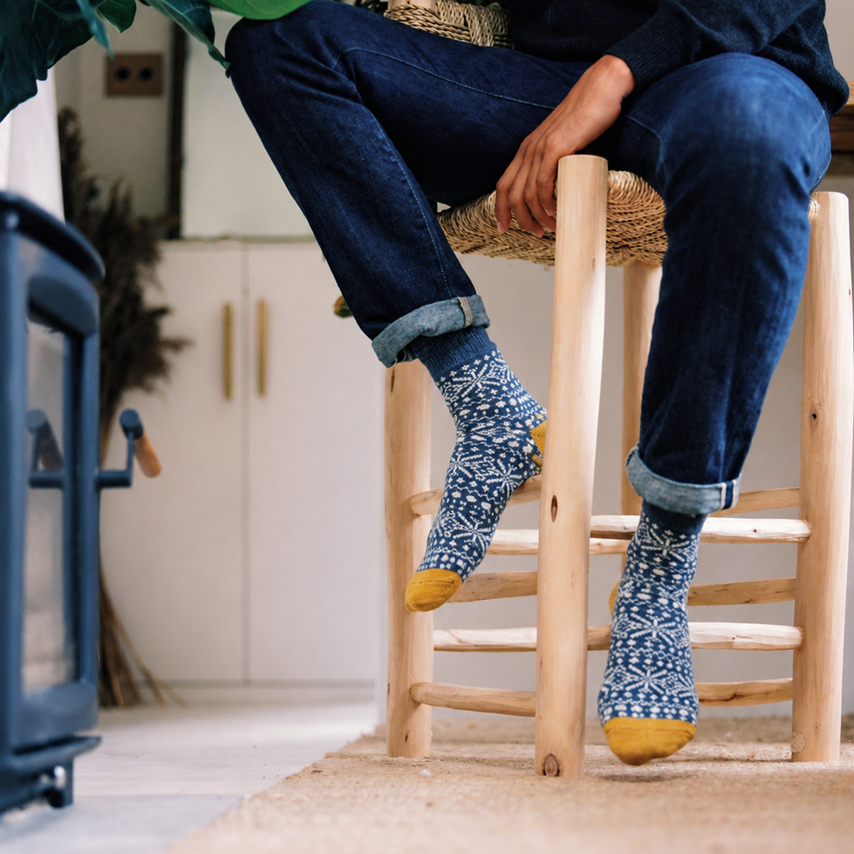 A person wearing A pair of navy blue knit socks with a white Nordic snowflake pattern and mustard yellow toes