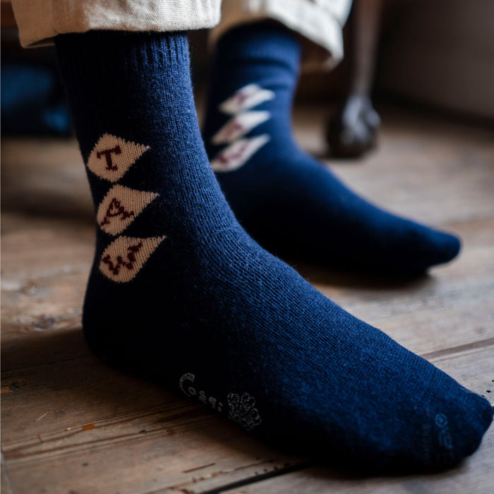 A pair of navy blue cashmere socks with a monogram pattern, showing the socks' texture and the brand name 'Corgi'.