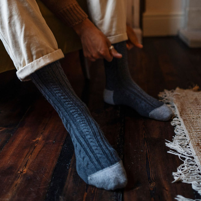 A pair of handmade fan cable pure cashmere socks in a mid-calf length displayed on a person's lower leg and foot, showing a textured knit pattern.
