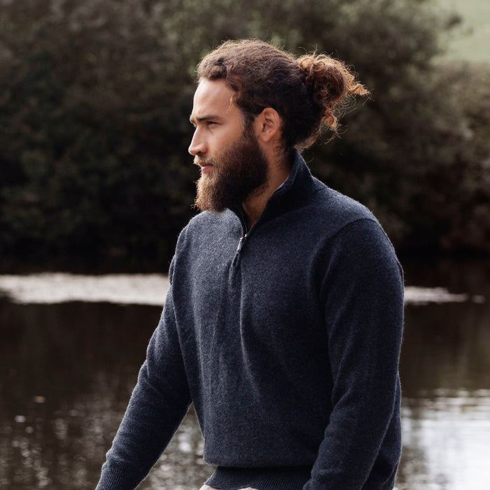 A man wearing a navy blue half zip sweater with a unique contrasting colour collar, standing outdoors.