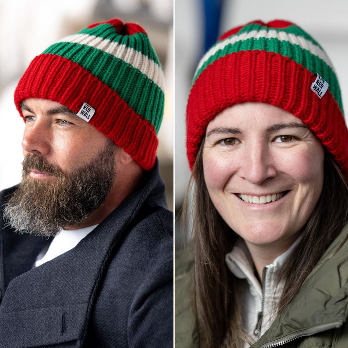 Two adults, one male and one female, wearing a red, green, and white striped wool beanie hat.