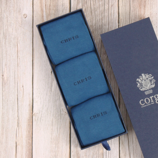Blue sock box with 'CHRIS' name on a wooden surface