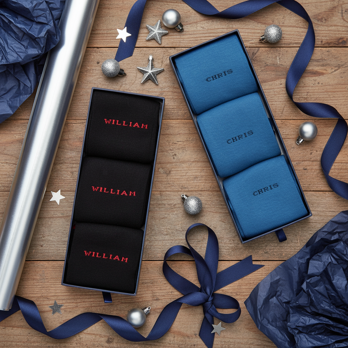 Two sets of personalized socks in gift boxes on a wooden surface with ribbons and ornaments.