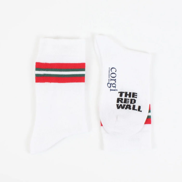 A pair of white crew socks with red and green stripes on the calf, featuring text 'RED WALL' and the flag of Wales.