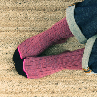 Purple pink socks with black toes worn on a woven surface
