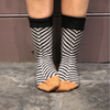 Person wearing black and white striped socks with gold toes on a stone floor.