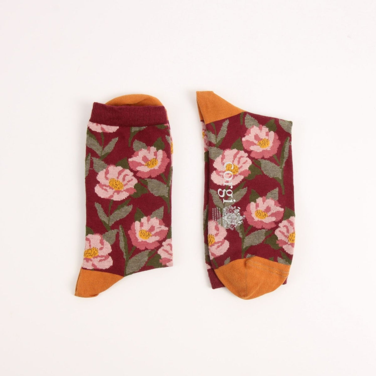 A pair of ankle socks with a burgundy floral print, featuring pink flowers, green leaves, and orange toes, heels, and cuffs, displayed flat on a white background.