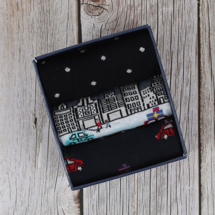 three pairs of men's socks with a Christmas-themed design, including a cityscape.
