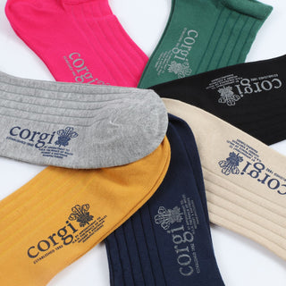 A collection of women's trainer socks in various colors, including black, pink, green, yellow, grey, and blue, all with the 'Corgi' brand logo on the side.