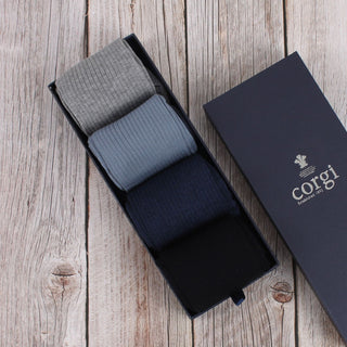 A set of men's cotton socks displayed next to their packaging box, with colors including navy, silver, and blue.