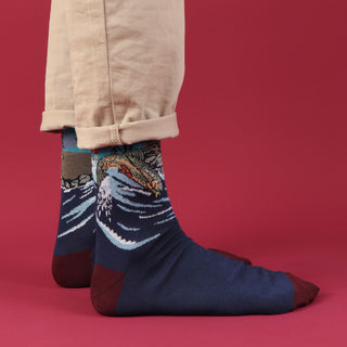 river scene socks worn with beige trousers on a red background.