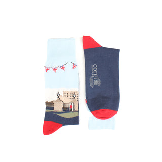A pair of men's socks with a detailed illustration of Windsor Castle, featuring a predominantly white cuff with a red ribbon design, a blue shaft, and red heel.