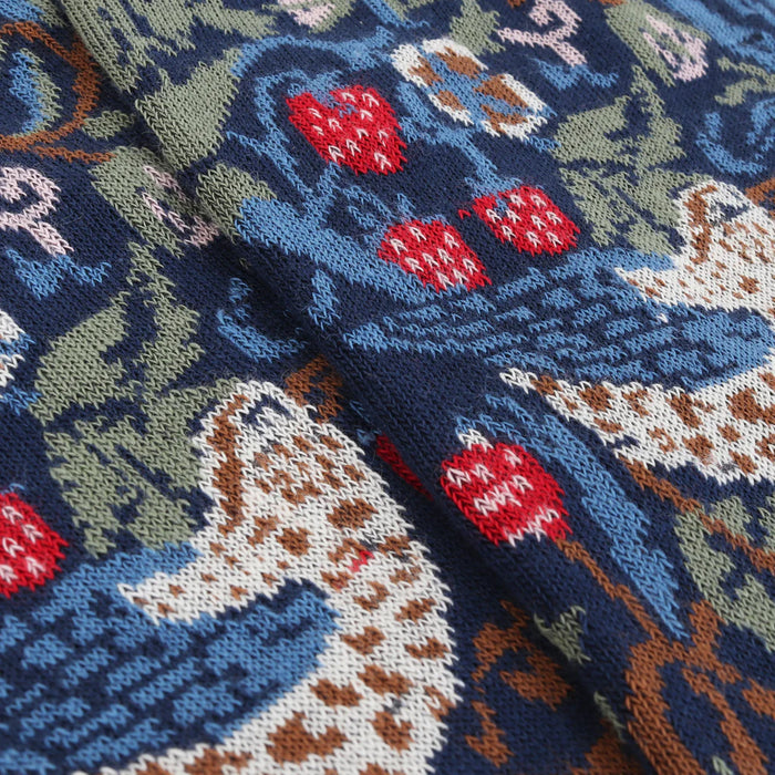 Close-up of a knitted fabric with floral and animal patterns.