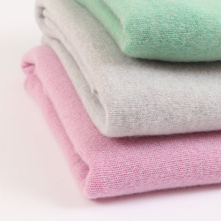 Stack of folded pastel-colored ponchos on a light background