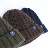 Three knit hats in green, brown, and navy on a white background