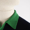 Close-up of a green collar on a black garment with a neutral background

