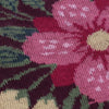 Close-up of a knitted fabric with pink flowers and green leaves.