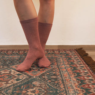 woman wearing rose pink melange cotton socks on a patterned rug