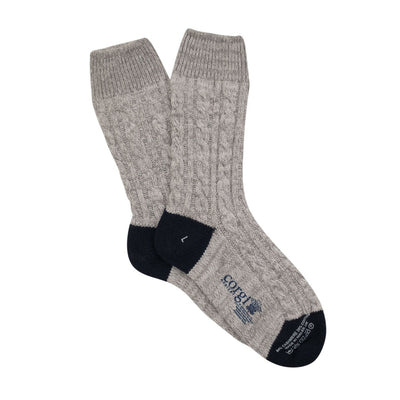 A pair of hand-knitted gray cable cashmere and cotton socks with the brand 'Corgi' visible.