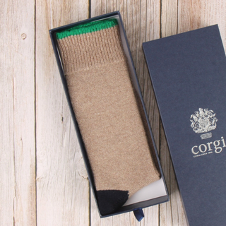 Beige sock with green tipping in an open box on a wooden surface, with 'corgi' branding visible.