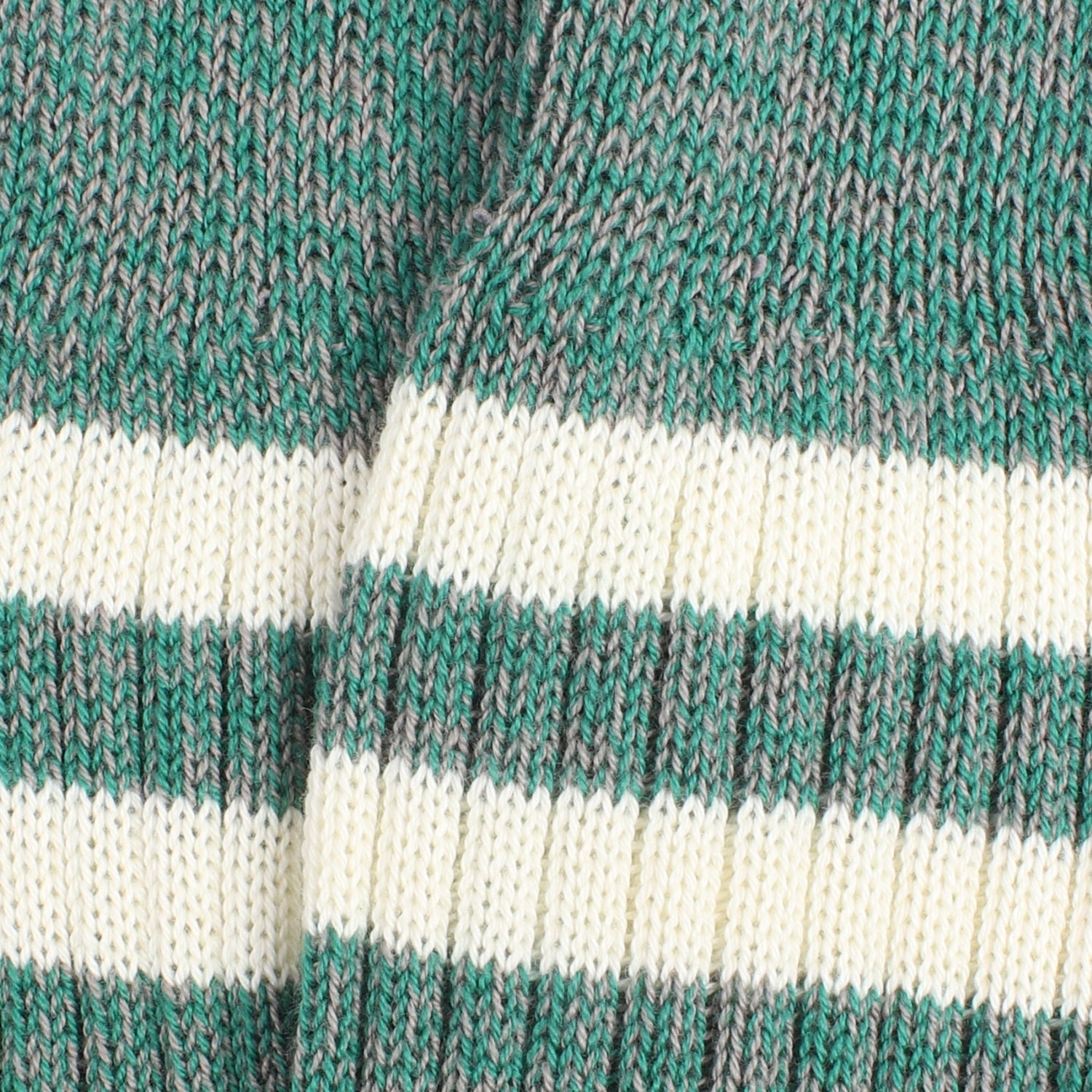 Close-up of a knitted sock made in a green and grey twist with two white stripes.