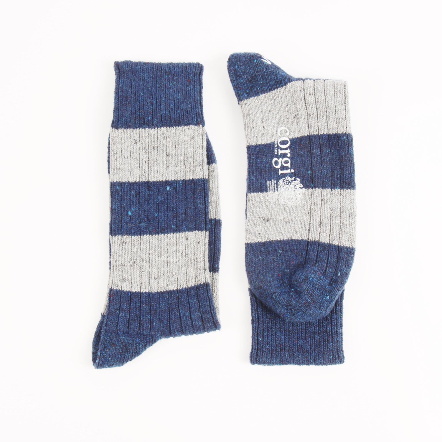 A pair of striped knit crew socks shown flat on a white background, with one sock displaying the toe and the other showing the side. The socks feature alternating horizontal stripes of navy blue and heather gray, with a white 'corgi' brand logo printed on the side.