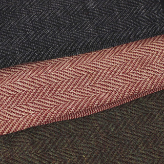 Close-up of a textured fabric with a herringbone pattern, featuring a dark gray and red color scheme.