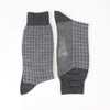 A pair of men's formal houndstooth merino wool socks in grey, showing the pattern and texture.